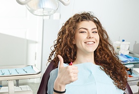 A young and smiling dental patient giving a thumbs up