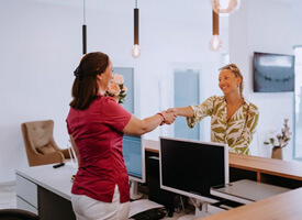 patient shaking hands with receptionist in dental office