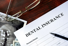 Dental insurance paperwork on desk with glasses and X-ray