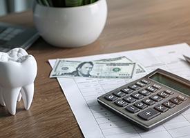 Large model tooth on desk next to calculator and dollar bills