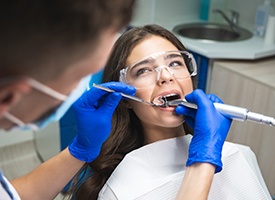 Woman undergoing root canal treatment performed by dentist in blue gloves