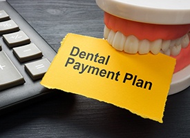 Artificial teeth biting yellow paper that says, Dental Payment Plan