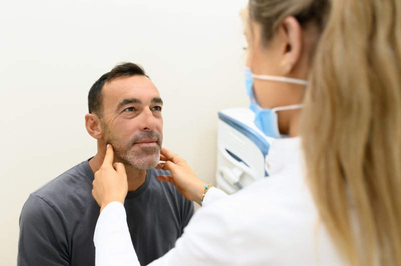 a dentist checking a patient’s jawline